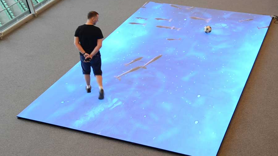 User interacting with a floor LED display by stepping on it at an event, demonstrating Visual Lab’s immersive interactive walkable screen technology.شخص يتفاعل مع شاشة LED أرضية من خلال المشي عليها في فعالية، مما يوضح تقنية الشاشات التفاعلية القابلة للمشي من فيجوال لاب.