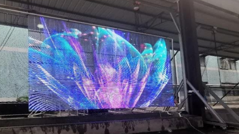 Suspended transparent LED display at an event by Visual Lab, delivering immersive digital visuals and high-impact presentation for exhibitions and live shows.شاشة إل إي دي شفافة معلقة في فعالية من فيجوال لاب، تقدم محتوى بصري غامر وعرضاً رقمياً عالي التأثير في المعارض والعروض الحية.